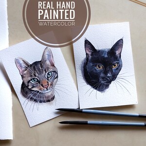 K&ouml;nnte beinhalten: Zwei Aquarellbilder von Katzen auf wei&szlig;em Karton. Die Katze links ist eine getigerte Katze mit gr&uuml;nen Augen. Die Katze rechts ist schwarz mit gelben Augen. Beide Katzen schauen den Betrachter an. Die Bilder sind mit "Real Hand Painted Watercolor" signiert.