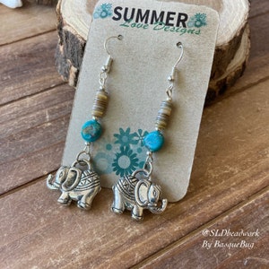 May include: Silver elephant charm earrings with turquoise and brown shell beads. The earrings are on a card that says "Summer Love Designs" and "@SLDheadwork By BasqueBug".