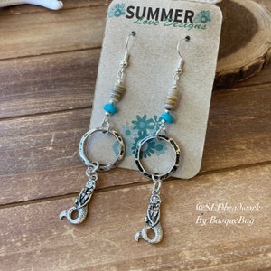May include: Silver mermaid dangle earrings with turquoise and shell beads. The earrings are on a card that says "Summer Love Designs" and "@SLDreadwork By BasqueBug".