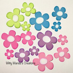 May include: A collection of colorful paper flower cutouts in various sizes. The flowers are in shades of green, blue, pink, and purple, each with a white center. The text "Witty Wanda's Creations" is at the bottom.