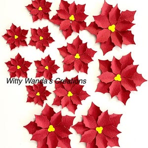 May include: A set of 12 red paper poinsettia flowers with yellow centers. The flowers are layered and have a textured surface.  Witty Wanda's Creations is printed on the bottom of the image.