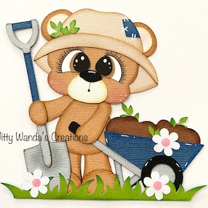 May include: A brown bear wearing a tan hat and holding a blue and silver shovel. The bear is pushing a blue wheelbarrow filled with soil and flowers. The image includes the text "Witty Wanda's Creations".