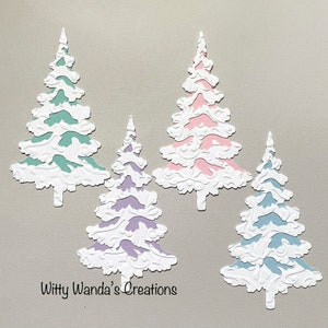 May include: Four die-cut Christmas trees in various colors: teal, pink, purple, and blue. Each tree has a white, textured, snow-like appearance. The text "Witty Wanda's Creations" is at the bottom.