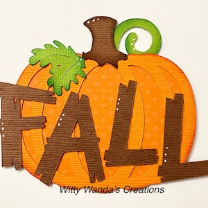 May include: A brown paper craft pumpkin with the word "FALL" cut out of it. The pumpkin is orange with white polka dots and a green leaf.