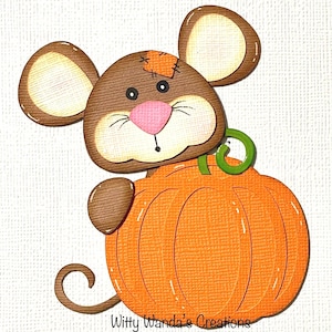 May include: A die-cut paper craft of a brown mouse with large ears, a pink nose, and a small orange patch on its head, peeking over a textured orange pumpkin with a green stem and a curled tail. The text Witty Wanda's Creations is at the bottom.