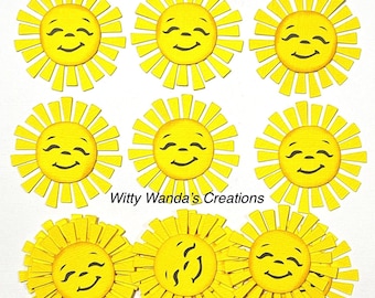 Puede incluir: Nueve recortes de sol amarillos con caras sonrientes y rayos radiantes. Los soles están dispuestos en un patrón de cuadrícula. El texto "Witty Wanda's Creations" está en la parte inferior.