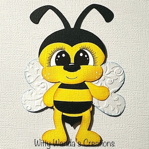 May include: A cute cartoon bee with big eyes and a yellow and black striped body. The bee has white wings with a floral pattern and is standing on a white background.
