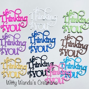 May include: Assortment of die-cut paper embellishments in various colors, each featuring the phrase "Thinking of You" in a decorative script font.