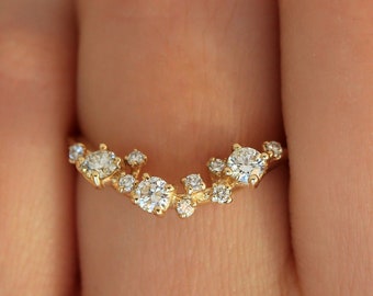 May include: A delicate gold band ring with a cluster of small diamonds set in a curved, crescent shape.