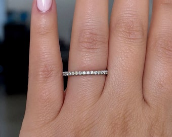 Könnte beinhalten: Ein zarter Diamant-Eternity-Ring mit einem dünnen Band und kleinen runden Diamanten, die in Pavé-Fassung gefasst sind.
