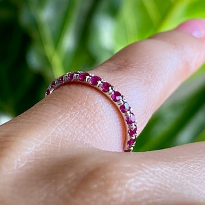May include: A silver band ring with a row of small, bright red ruby stones.