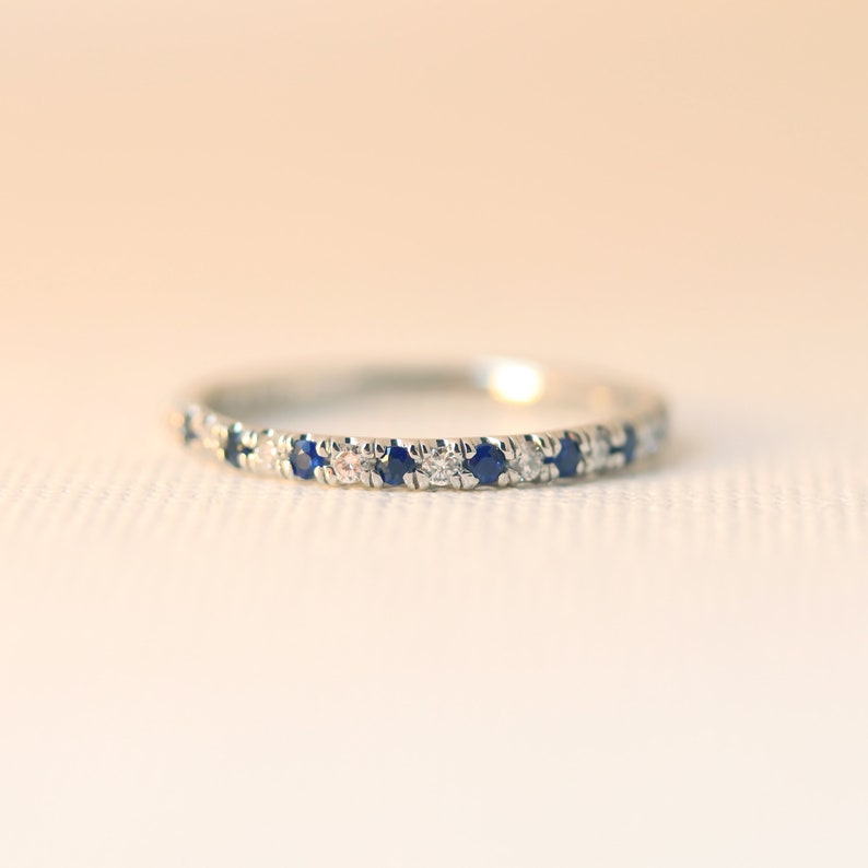 May include: A delicate silver band ring with alternating blue sapphires and white diamonds.