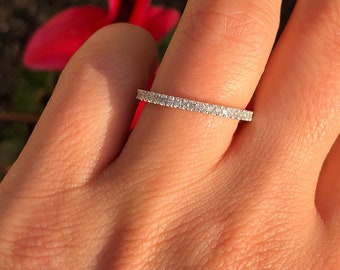 Könnte beinhalten: Ein dünner, zarter Silberring mit einer Reihe kleiner, klarer Diamanten in Pavé-Fassung.