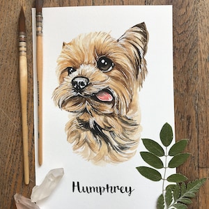 May include: Watercolor painting of a brown and tan Yorkshire Terrier with its tongue sticking out. The dog's name, Humphrey, is written in black cursive below the dog.
