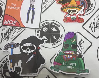 Könnte beinhalten: Eine Sammlung farbenfroher Aufkleber mit Motiven zum Thema Elektriker. Die Aufkleber zeigen unter anderem einen Totenkopf mit Sombrero, einen Sensenmann mit Hammer und einen Zombie. Einige Aufkleber tragen die Aufschrift "Spirit Sparky" und "Sgt. Nuts - WOE".
