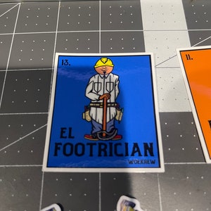 May include: A blue and white sticker with a cartoon illustration of a construction worker wearing a yellow hard hat and holding a tool. The sticker says "El Footrician" and "Workrew" in black text.