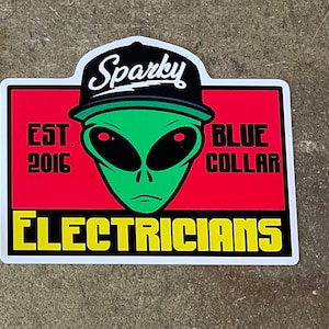 May include: A sticker with a green alien wearing a black baseball cap with the word "Sparky" on it. The alien has red eyes and a serious expression. The sticker also has the text "EST. 2016" and "BLUE COLLAR ELECTRICIANS" in black and yellow lettering on a red background.