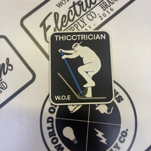 May include: Black and white sticker featuring a cartoon electrician riding a scooter. The sticker reads "THICCTRICIAN" and "W.O.E" in white text. The sticker is on a white background with a black and white logo that says "WORLD OF SUPPLY CO."
