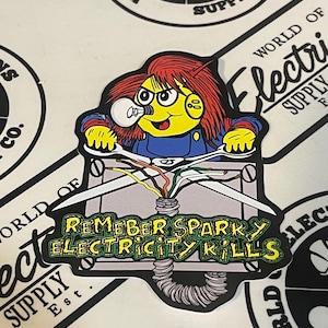 May include: A red-haired cartoon character with a light bulb nose holds a pair of wire cutters over a junction box. The text "REMEBER SPARKY ELECTRICITY KILLS" is written in green and yellow letters on the junction box.