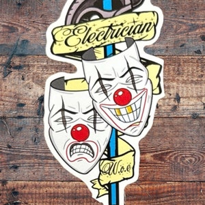 May include: A sticker with a blue and white wrench, two clown masks, and a yellow banner that says "Electrician W.o.e."