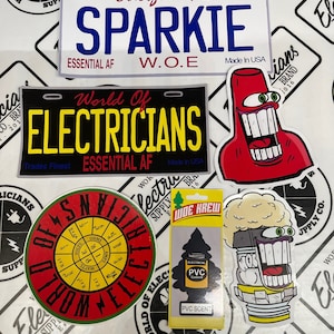 May include: A collection of stickers and car air fresheners with an electrician theme. The stickers feature a red cartoon character with a toothy grin, a black and yellow sticker with the words "World of Electricians" and a red and yellow sticker with a compass-like design. The air freshener is a pine tree design with the words "WDE KREW" and "PVC Scent".