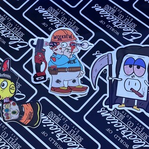 May include: Three colorful stickers featuring cartoon characters. The first sticker is a yellow cartoon character with a light bulb head and a blue and red body. The second sticker is a cartoon character wearing a blue shirt and a hard hat with the text "Wokrew" on it. The third sticker is a cartoon character wearing a black hooded robe and holding a scythe. The text "World of Electricians Supply Co. Brand Est. 2016" is on each sticker.