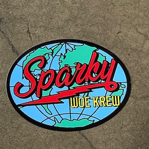 May include: A blue and green globe sticker with a red lightning bolt and the text "Sparky Woe Krew" in red and yellow letters.