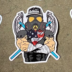 May include: A sticker featuring a cartoon character wearing a gas mask, a bandana with stars and stripes, and a baseball cap that says "World of Electricians". The character is holding two crossed wrenches.