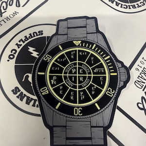 May include: A sticker shaped like a wristwatch with a gray band and a black face. The watch face features a yellow electrical engineering power wheel diagram with formulas for Watts, Volts, Amps, and Ohms, including P, E, I, and R variables.