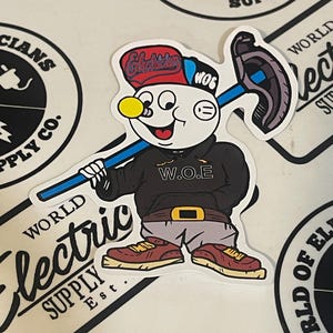 May include: A sticker featuring a cartoon character in a black hoodie with "W.O.E" on it, gray pants, and brown shoes. The character wears a red cap with "Electrician" on it and holds a blue and gray tool. The sticker is surrounded by other stickers.