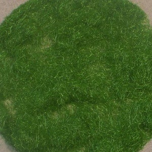 Może przedstawiać: Zbliżenie na okrągły kawałek sztucznej trawy w kolorze zielonym.