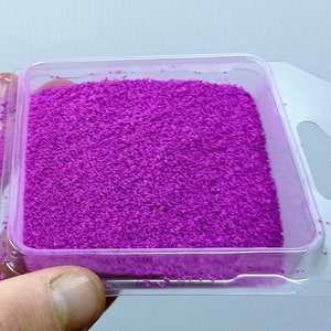 Può includere: Un piccolo contenitore di plastica pieno di polvere viola brillante.