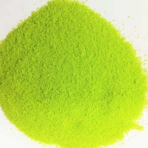 Può includere: Una vista ravvicinata di un mucchio di sabbia fine di colore verde brillante. La sabbia è distribuita uniformemente e sembra essere molto fine.