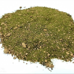Op de afbeelding: Een close-up van een hoop groene en bruine aarde, waarschijnlijk voor gebruik in een terrarium of miniatuurtuin.