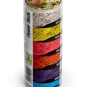 May include: A clear plastic container filled with six different colors of flower flock. The colors are white, yellow, pink, red, violet, and light blue. The container is labeled "Flower Flock".