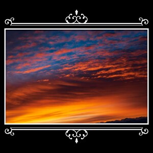 Puede incluir: Un vibrante atardecer con vetas de naranja, rojo y azul llena el encuadre. El cielo está enmarcado por un borde blanco con adornos decorativos sobre un fondo negro. La imagen captura la belleza de un cielo colorido.
