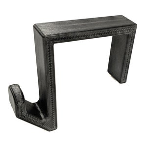 May include: Black plastic hook with a decorative border. The hook has a rectangular shape with a curved hook at the bottom.