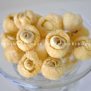 May include: A close-up of a bowl filled with dried lotus seeds. The seeds are light brown and have a slightly wrinkled texture.