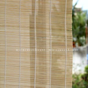 May include: Close-up of a bamboo window shade. The shade is made of thin, light brown bamboo slats woven together with vertical white threads. The text "miensweethouse" is visible on the shade.