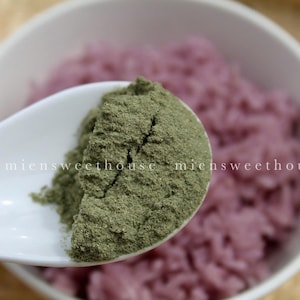 Peut inclure: Une cuillère blanche contient une cuillerée de poudre verte au-dessus d'un bol de riz violet. Le texte "miensweethouse" est visible sur la cuillère.