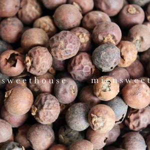 Peut inclure: Une image en gros plan d'un tas de baies de genièvre séchées. Les baies sont de couleur brun foncé et ont une texture légèrement ridée.