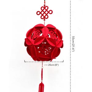 May include: Red felt Chinese New Year lantern with a knotted tassel and a red tassel hanging from the bottom. The lantern is 21.6 inches tall and 8 inches in diameter.