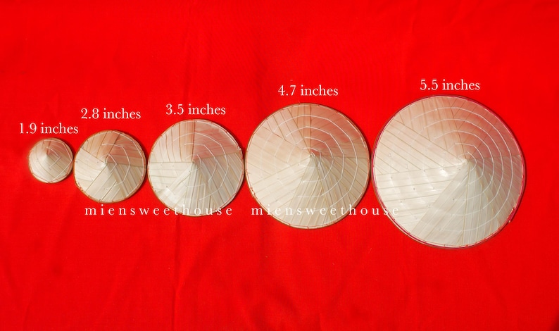 May include: Five conical hats of varying sizes, ranging from 1.9 to 5.5 inches in diameter, are displayed against a vibrant red background. The hats are made of woven straw and are arranged in a row. The text "miensweethouse" is visible.