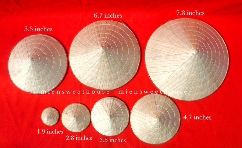 May include: A collection of conical straw hats in various sizes, ranging from 1.9 inches to 7.8 inches in diameter. The hats are arranged on a red background, showcasing their traditional design and craftsmanship. The hats are made of woven straw.