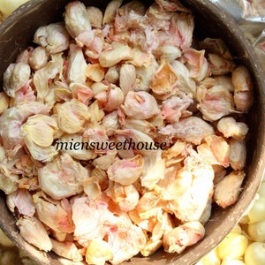 May include: A close-up of a bowl filled with dried, pale pink and white garlic cloves. The garlic is in a wooden bowl and is ready to be used in cooking.