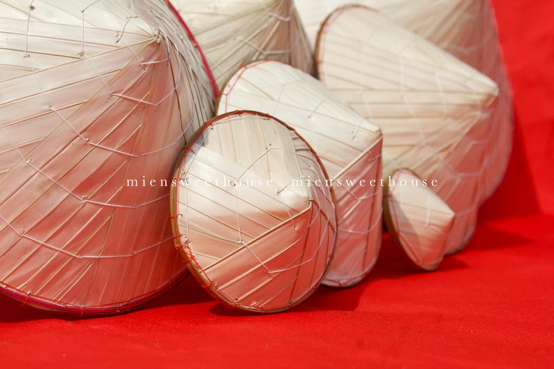 May include: A collection of woven straw hats in various shapes and sizes, arranged on a vibrant red surface. The hats are made of light-colored straw and feature a distinctive woven pattern. The image includes the text "miensweethouse".