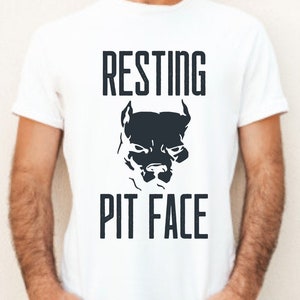 Puede incluir: Camiseta blanca con una silueta negra de la cara de un perro pitbull y el texto "RESTING PIT FACE" impreso en la parte delantera.