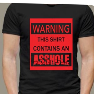 May include: Black t-shirt with a red warning sign that says "WARNING THIS SHIRT CONTAINS AN ASSHOLE".