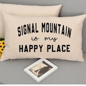 May include: Two beige throw pillows with the text "SIGNAL MOUNTAIN is my HAPPY PLACE" printed in black on the front pillow.