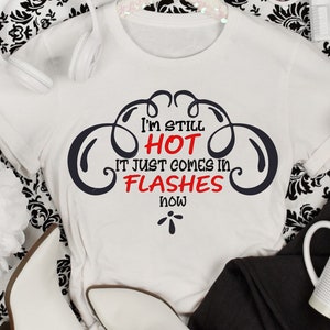 May include: White t-shirt with a black graphic that says "I'm still hot it just comes in flashes now".
